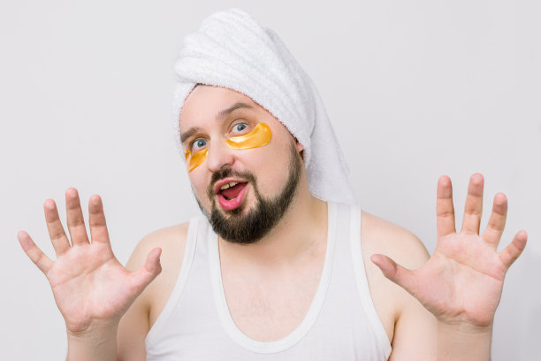 这张照片上的男子满脸胡须，头上戴着白色的毛巾，眼睛上戴着金色的眼罩。男士Spa护肤图片下载
