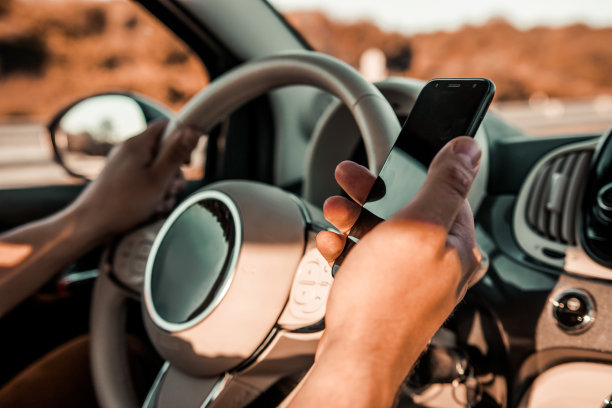 一名男子驾驶着一辆有或没有手机的汽车，握着方向盘图片下载