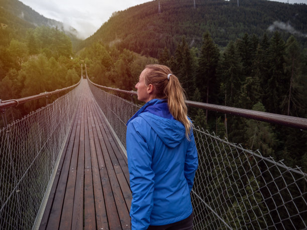 一名女子在瑞士松树谷的吊桥上行走图片下载
