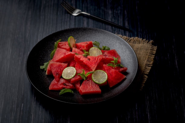新鲜的西瓜沙拉保存在一个黑色的盘子在黑色的背景图片下载
