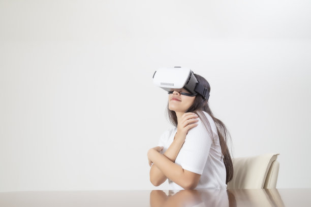 年轻女子在白色背景下戴着虚拟现实设备或虚拟现实眼镜表演。图片下载