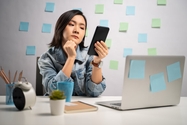 亚洲女人看智能手机读新闻无聊和困在家里的办公室。亲密。居家办公预防COVID-19概念。图片下载