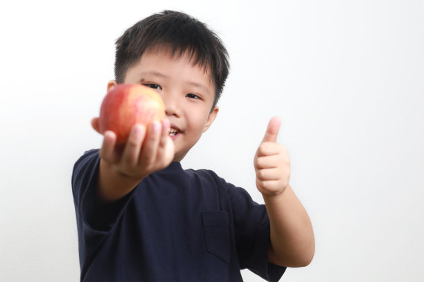 男孩在白色背景下吃苹果图片下载