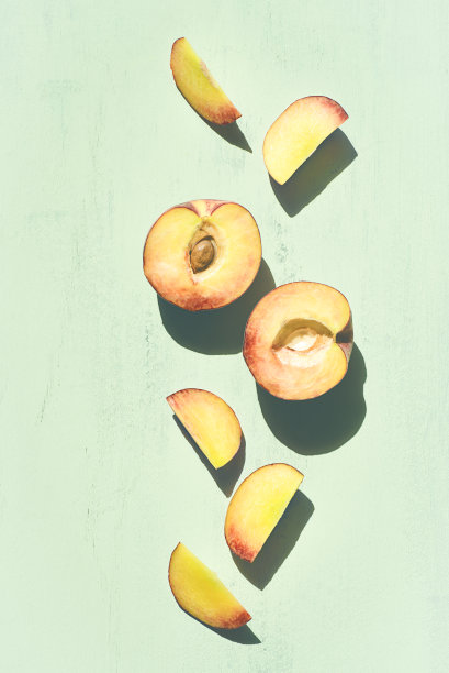 切好的桃子片在绿色薄荷的背景下有清晰的阴影。夏天的水果图片下载