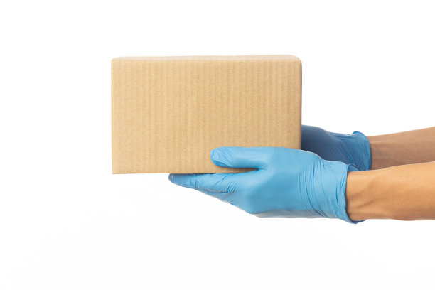 近距离送货员手在医疗手套持有纸板盒隔离在白色背景，包装模型，送货服务概念图片下载