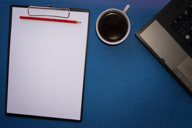 蓝色的办公桌桌子与库存照片和设计与空白笔记本电脑，电脑，项目和一杯咖啡。顶部视图与复制空间。平坦的地板上。图片下载