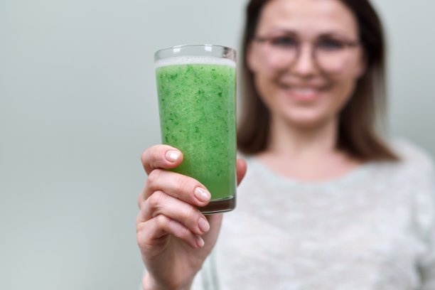 靠近玻璃与绿色天然蔬菜冰沙饮料在女人的手图片下载