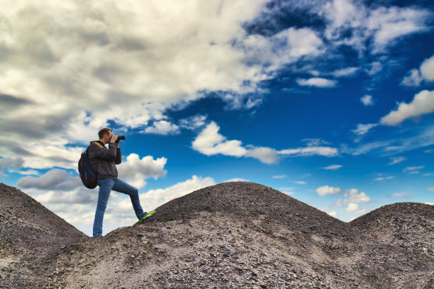 一个背着背包的男人正在山里拍风景照片图片下载