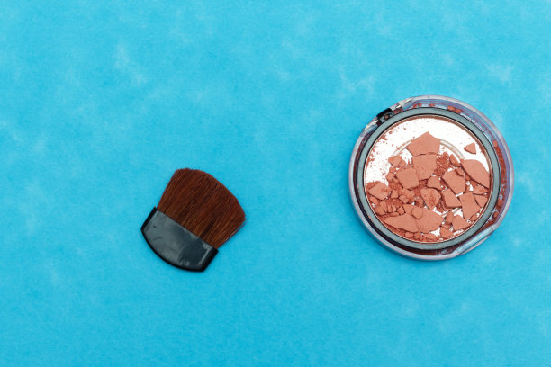 破碎的腮红和刷子孤立的蓝色背景图片下载