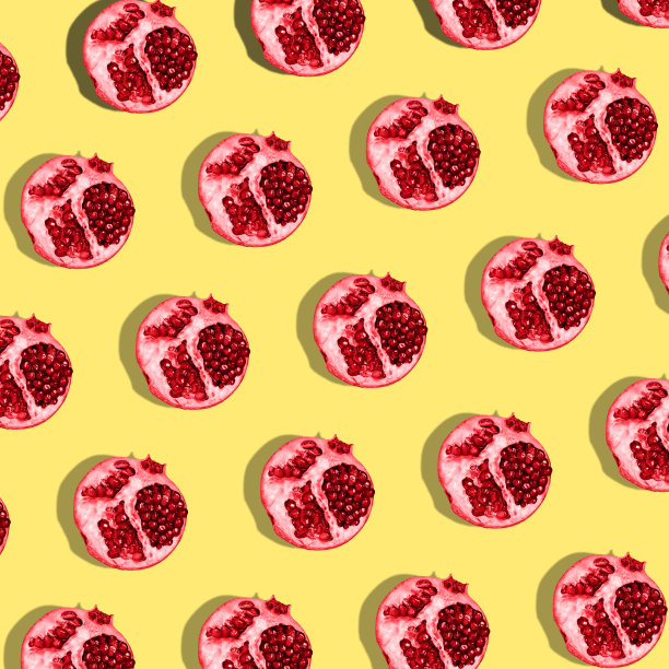 红色的石榴果在黄色的背景上。水果模板。最小的概念图片下载