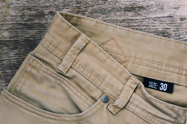 米色牛仔裤，木制背景。40号的标签。男女服装图片下载