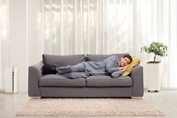 穿着睡衣的男人睡在客厅的沙发上图片下载