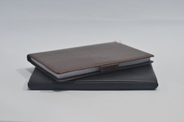 逼真的黑色和棕色皮革笔记本模型在浅白色的背景。图片下载
