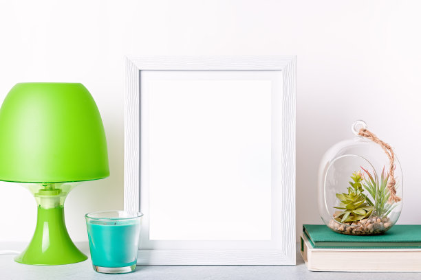 仿相框，台灯，多肉植物，白色书桌上的书，复印空间。家庭内部装饰在绿色的颜色，正面视图图片下载