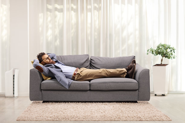 一个长胡子的男人躺在客厅的灰色沙发上图片下载