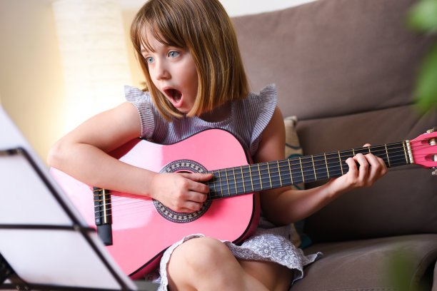惊讶的女孩一边练习吉他一边看乐谱图片下载