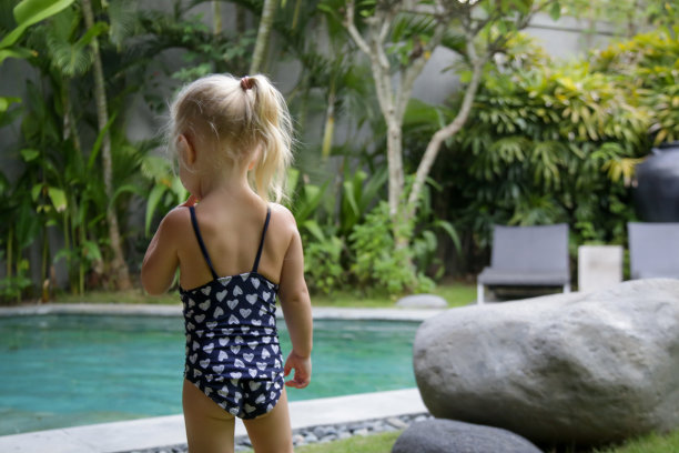 两岁蹒跚学步的小女孩在游泳池享受一天的偷拍照片图片下载