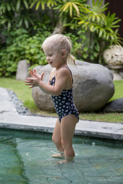 两岁蹒跚学步的小女孩在游泳池享受一天的偷拍照片图片下载