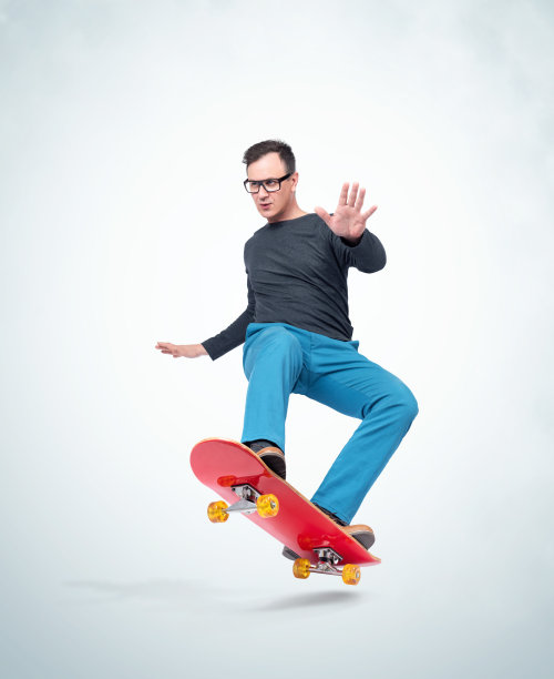 情绪化的男人穿着休闲的衣服在滑板上玩极端，孤立在光的背景。图片下载