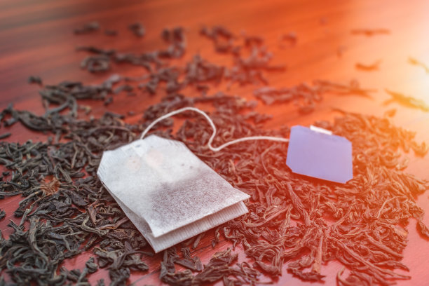 带标签的茶包，躺在早晨阳光下的大红茶叶子上图片下载