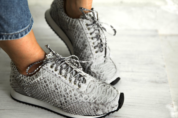 穿着时尚巨蟒运动鞋的女人靠近彩色墙。空间的文本图片下载