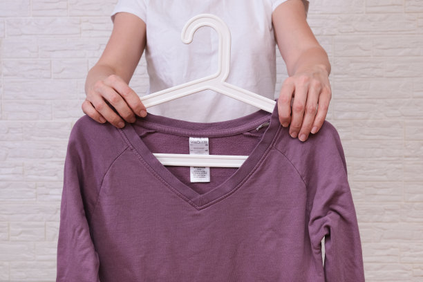 白种女人在挑选衣服，她拿着一个淡紫色长袖衣架，购物，试穿，买打折概念的衣服，廉价的二手衣服在网上出售图片下载