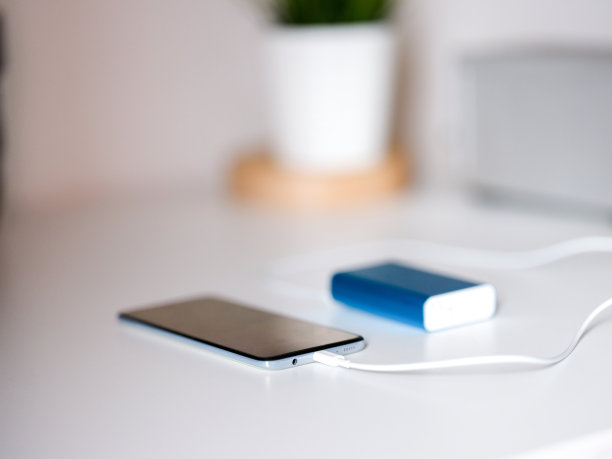 智能手机充电与蓝色Powerbank与白色背景图片下载