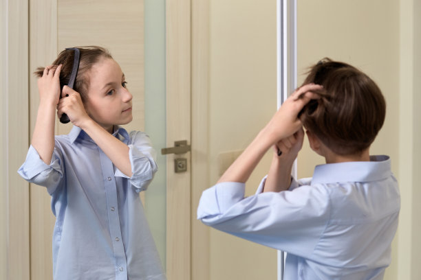 一个黑发男孩在镜子前用梳子梳头发。图片下载