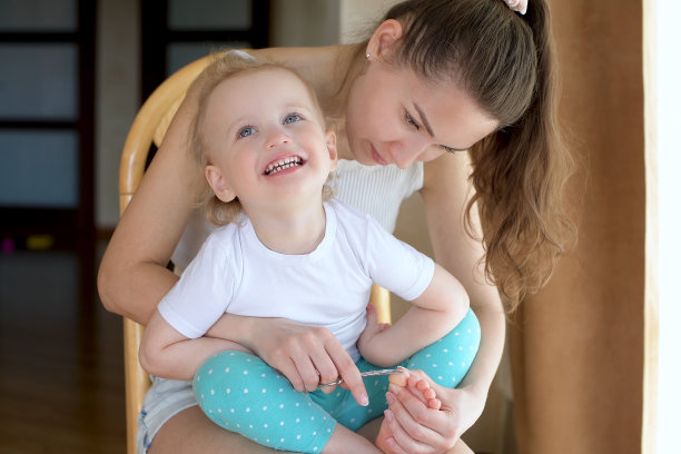 母亲给小女儿剪脚趾甲。妈妈和宝宝花时间在一起图片下载