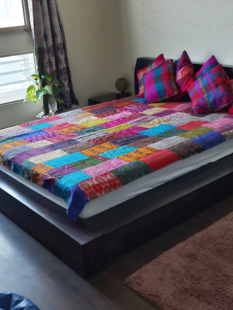 床头板上斜倚着色彩鲜艳的散垫，墙上挂着仙女般的灯光，拼花图案的被子，五彩缤纷的床罩图片下载