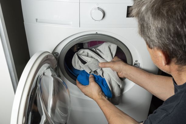 男性在洗衣机内放置衣物的近距离观察。国内常规的概念。图片下载