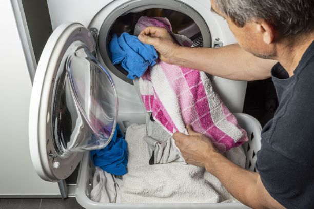 男性在洗衣机内放置衣物的近距离观察。国内常规的概念。图片下载