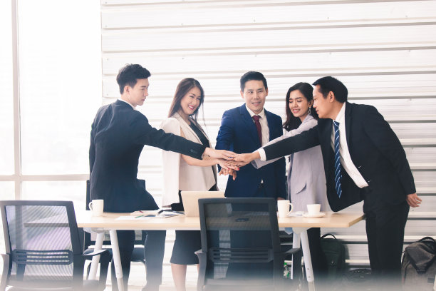 年轻的亚洲商人们一起鼓掌。堆栈的手中。团结协作的理念。团队合作，携手共进的理念图片下载