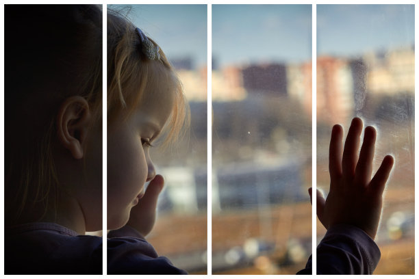 孤独的孩子在隔离条件下望着窗外图片下载