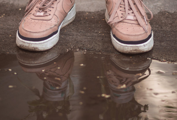 Ð:一对相爱的年轻夫妇的双脚翘起。在水坑里有倒影的运动鞋图片下载