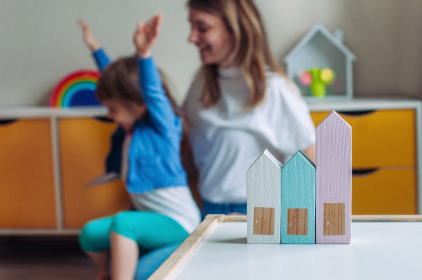 孩子们房间里的桌子上有木制的玩具房子。散焦快乐的家庭妈妈和女儿一起玩图片下载