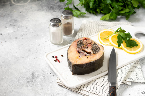 浅灰色的餐桌上，白色陶瓷盘子上放着野生鲟鱼排。健康的海鲜。带有文本空间图片下载