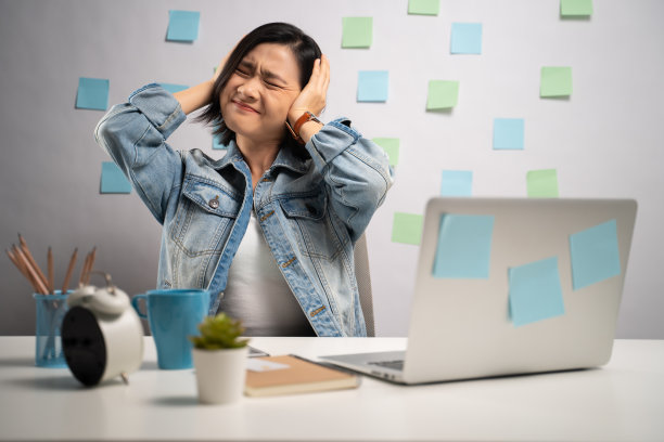 一名亚洲女性在笔记本电脑上工作，在家里的办公室捂着耳朵感到无聊和厌烦。亲密。居家办公预防COVID-19概念。图片下载