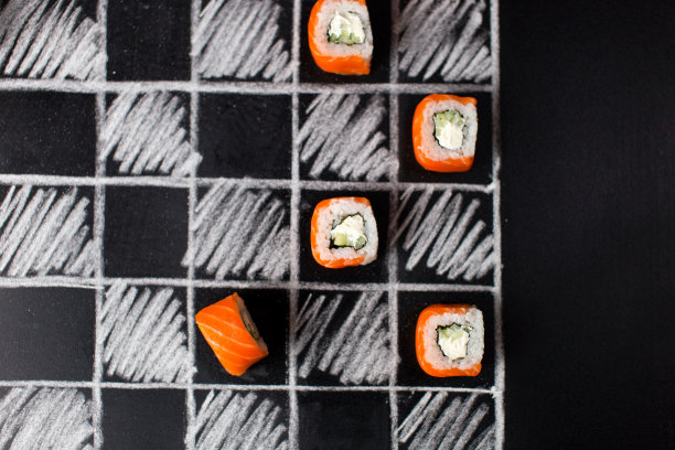 日式寿司配三文鱼、黄瓜和奶油芝士手绘棋盘。食物和游戏创意概念图片下载