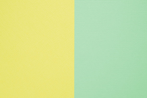成纸的背景。背景是黄色和精致的薄荷色，垂直等分。图片下载