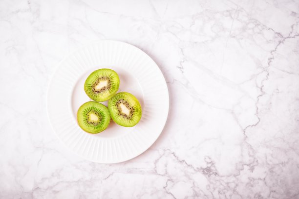 三瓣成熟的猕猴桃放在灰白的大理石背景上图片下载