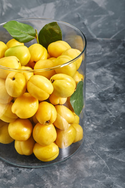 玻璃花瓶里放着新鲜的黄色杏子。水果在一个灰色的背景俯视图。复制空间，抽象，照片的杂货店图片下载