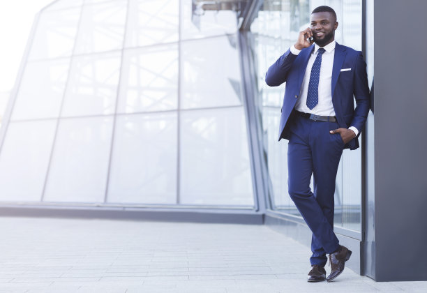 西装革履的微笑企业家站在城市里打电话图片下载