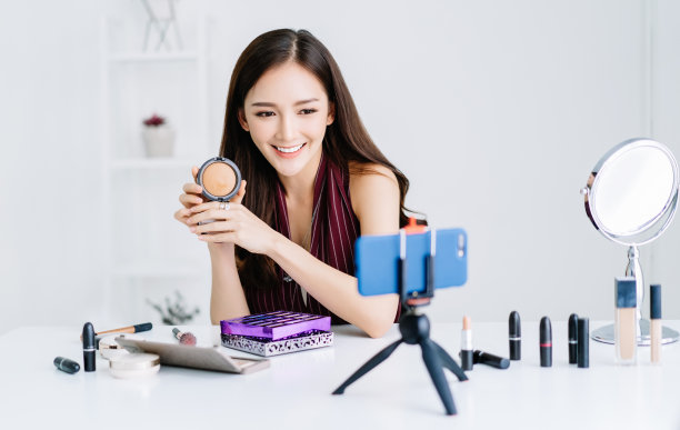 年轻的亚洲美容时尚视频博主或博主在做化妆教程视频在线营销，并在家庭办公室的社交网络上直播视频。女人生活方式化妆博客概念。图片下载