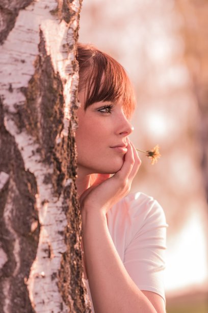 美丽的女孩带着花在大自然的树干上做梦图片下载