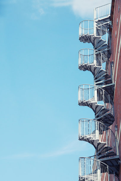 螺旋楼梯在建筑的墙壁上，对着蓝天图片下载