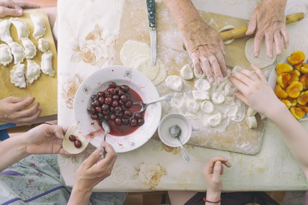 俯视图厨房桌子上一个面目全非的家庭正在准备自制饺子，真实的生活方式，俯视图。传统的民族美食。图片下载