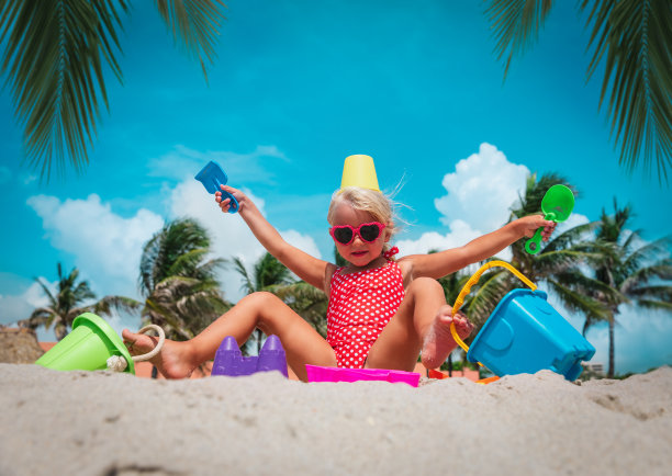 快乐的小女孩在热带海滩上玩玩具图片下载