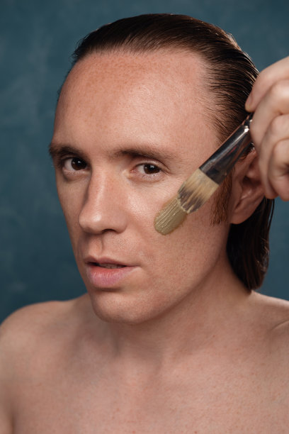 一个长头发的男人正在敷一个绿色的粘土面膜图片下载