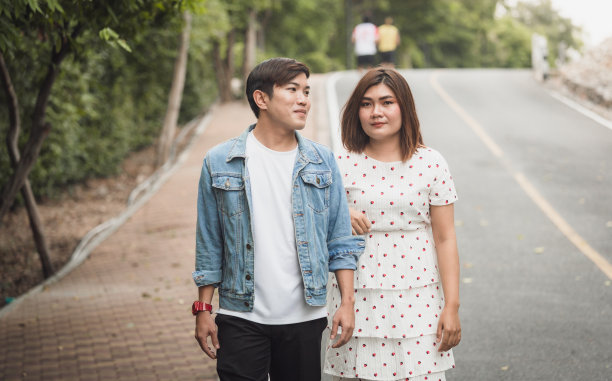 年轻的亚洲情侣浪漫地一起在公园里散步图片下载